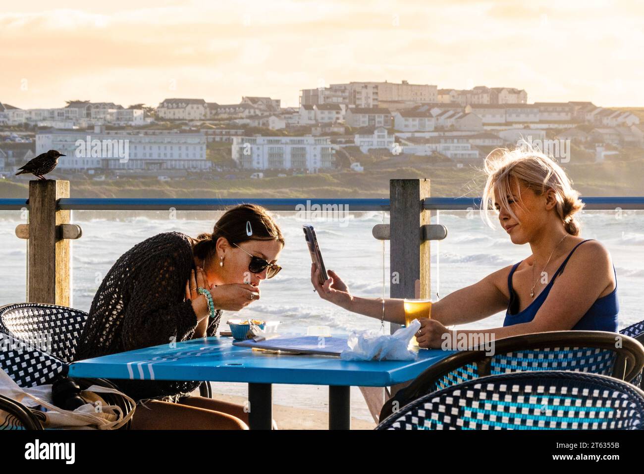 Zwei Freundinnen sitzen auf dem Terrassenbereich der Fistral Beach Bar in Newquay in Cornwall in Großbritannien. Stockfoto