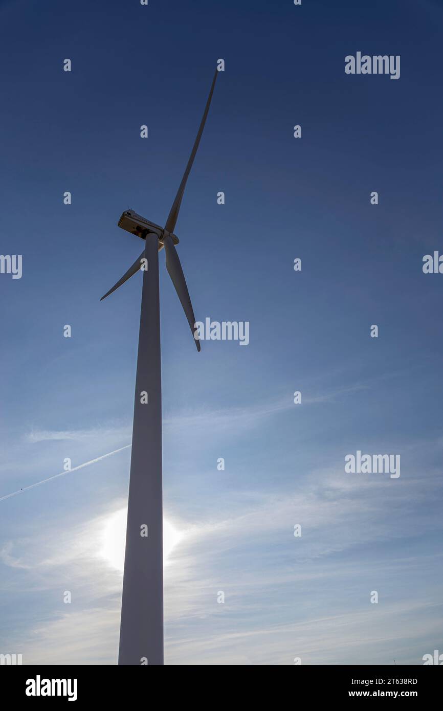 Nahaufnahme einer Windmühle. Blauer Himmel und die Sonne im Hintergrund. Vertikales Foto. Erneuerbare Energien. Umweltschutz Stockfoto