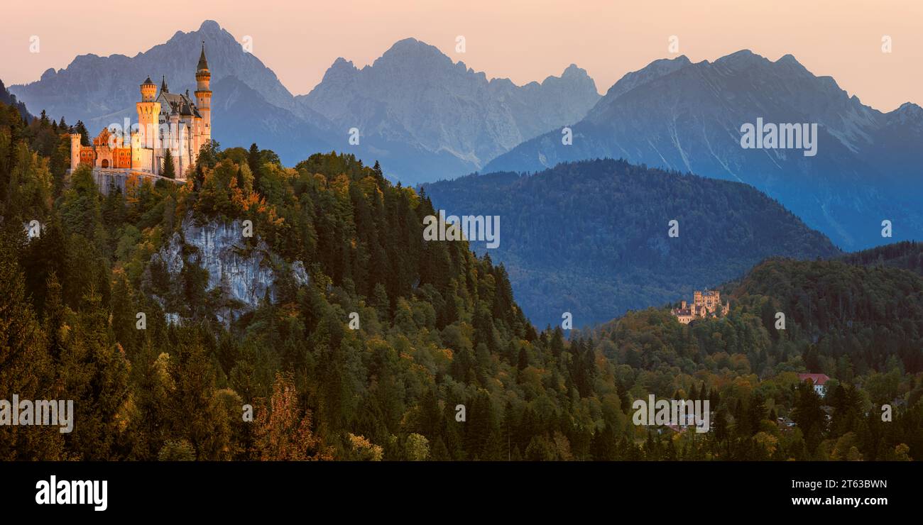 Ein breites 2:1-Panoramabild von Schloss Neuschwanstein, beleuchtet nach Sonnenuntergang, umgeben von Herbstfarben, in der Nähe der Stadt Füssen, in Th Stockfoto