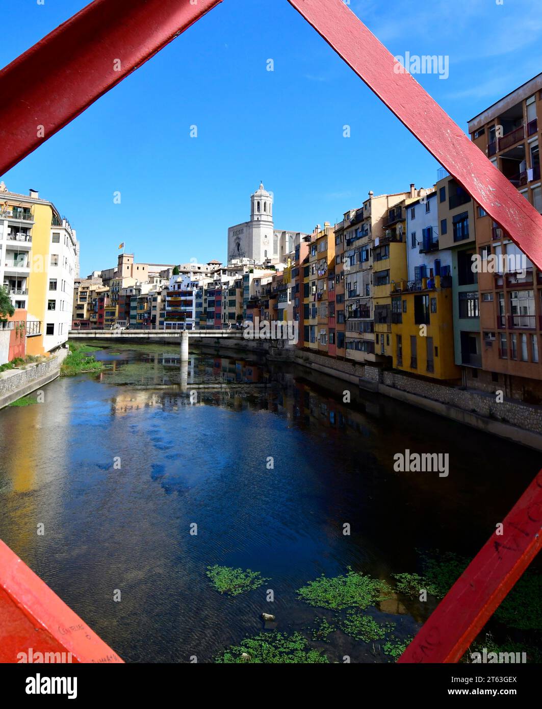 Girona, mit der Struktur der Pont de les Peixateries Velles über dem Onyar River mit Gironas strenger Kathedrale, die über die bunten Dächer hinausragt Stockfoto