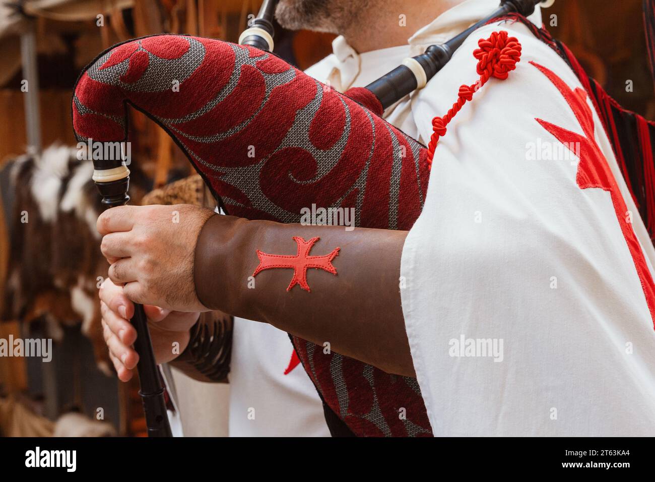 Nahaufnahme eines anonymen mittelalterlichen Reenactor-Arms, der mit einem roten Muster bedeckt ist und ein Musikinstrument mit einem roten Kreuz auf dem Fo tätowiert hält Stockfoto