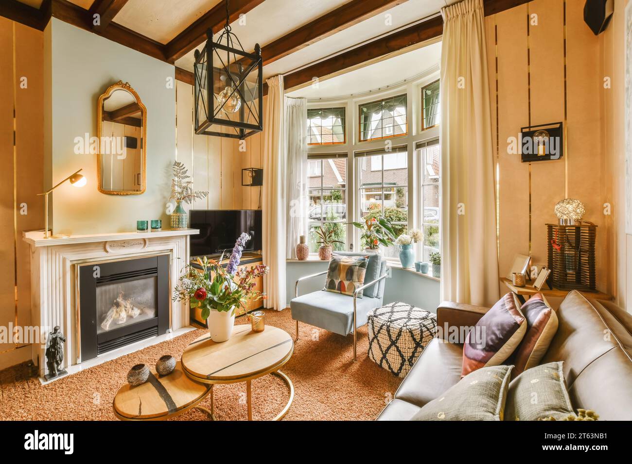 Bequemer Stuhl und Sofa vor Kamin und Fernseher durch helles Fenster in einem modernen Wohnzimmer zu Hause Stockfoto