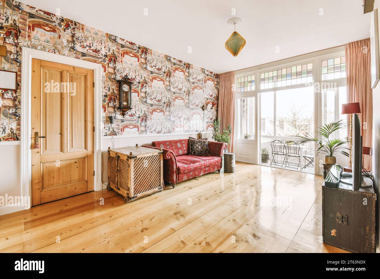 Rotes leeres Sofa mit Schrank vor dem Fernseher durch helles Fenster im geräumigen Wohnzimmer des modernen Apartments Stockfoto