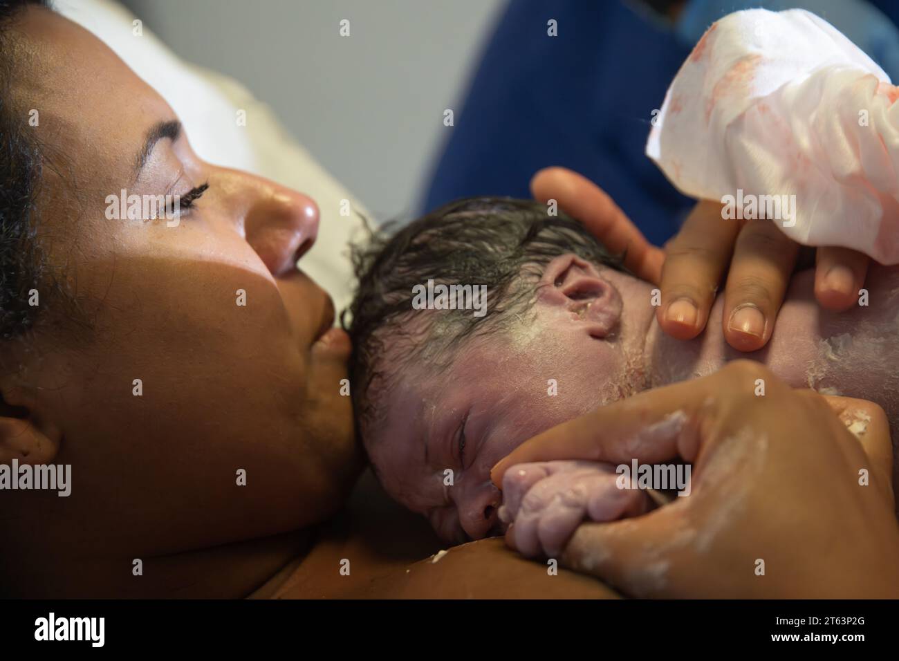 Eine Nahaufnahme einer Mutter, die ihr neugeborenes Baby liebevoll hält und die ersten Momente der Mutterschaft schätzt Stockfoto