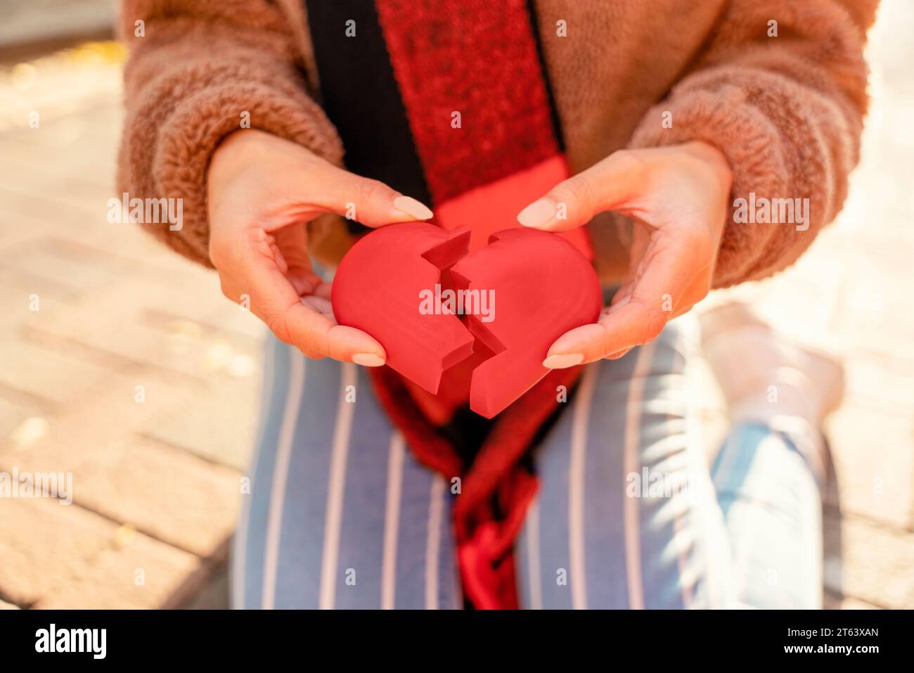 Frauenhände, die ein rotes gebrochenes Herz halten. Ein Scheidungskonzept zu bekommen Stockfoto