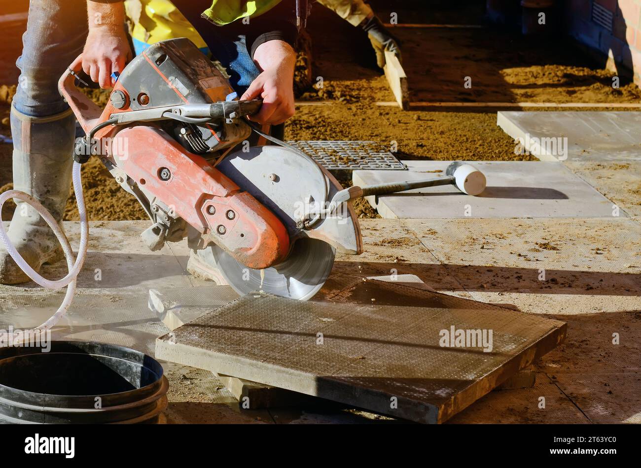 Baumeister schneidet Betonplatten mit einer Betonsäge und einer Diamantklinge während der Arbeit auf externen Fußwegen aus der Nähe Stockfoto