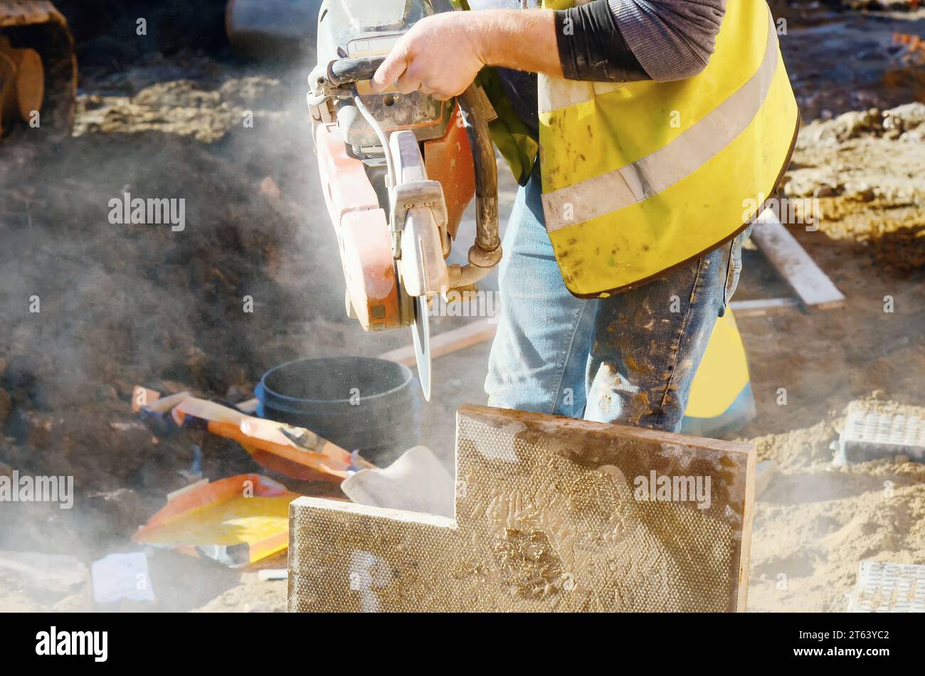 Baumeister schneidet Betonplatten mit einer Betonsäge und einer Diamantklinge während der Arbeit auf externen Fußwegen aus der Nähe Stockfoto