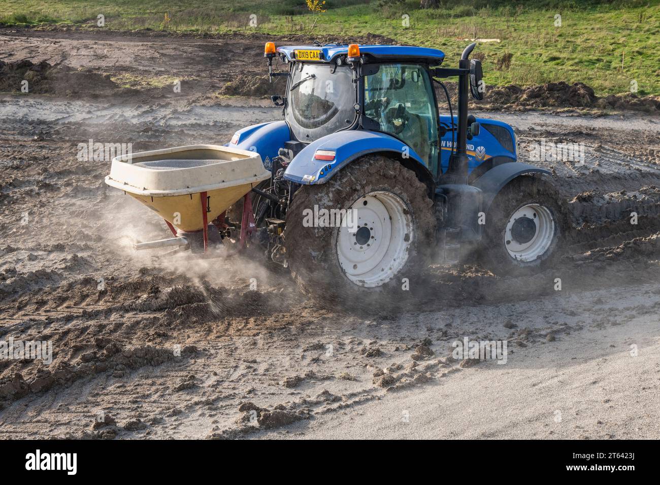 Verwenden eines Traktors mit Düngemittelstreuer zum Auftragen einer Dichtschicht aus Natriumbentonit-Tongranulat, um einen neu gegrabenen Teich abzudichten (UK) Stockfoto