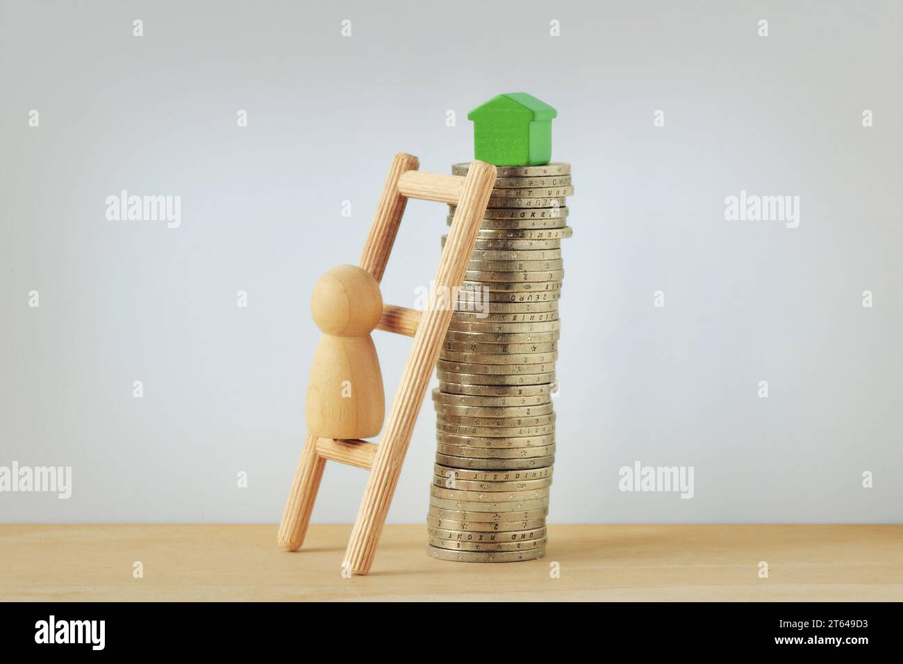 Holzpfand, der eine Leiter hinaufklettert, um ein kleines Gewächshaus auf dem Münzturm zu erreichen - Konzept des Kaufens eines Hauses Stockfoto