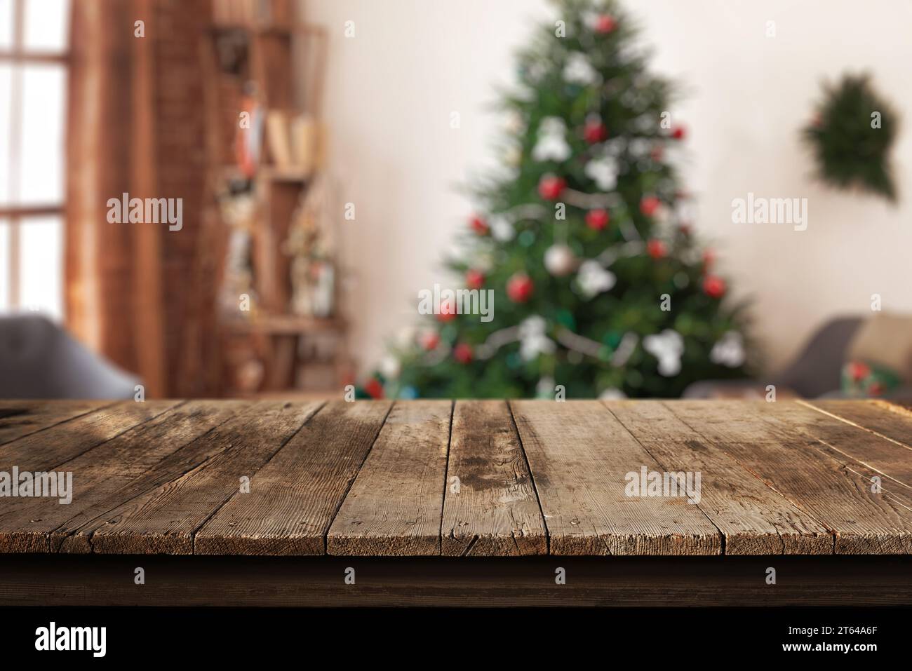 Holzschreibtisch in einem Wohnzimmer mit einem Weihnachtsbaum und festlichen Dekorationen im Hintergrund. Perfekter Ort für einen warmen und einladenden Urlaubs-geldautomaten Stockfoto Holzschreibtisch in einem Wohnzimmer mit einem Weihnachtsbaum und festlichen Dekorationen im Hintergrund. Perfekter Ort für einen warmen und einladenden Urlaubs-geldautomaten Stockfoto