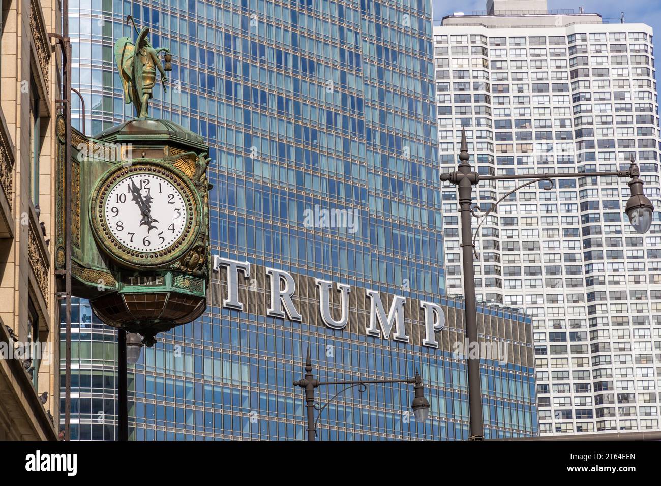 Die Uhr im Juweliergebäude wird kurz vor Hochmittags angezeigt. Im Hintergrund sehen Sie die Schrift Trump aus dem Trump Tower. Chicago, Usa Stockfoto