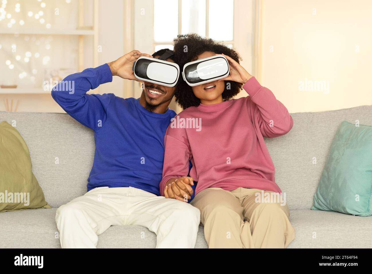 Afroamerikanische Ehepartner, die im Wohnzimmer Virtual-Reality-Headsets tragen Stockfoto