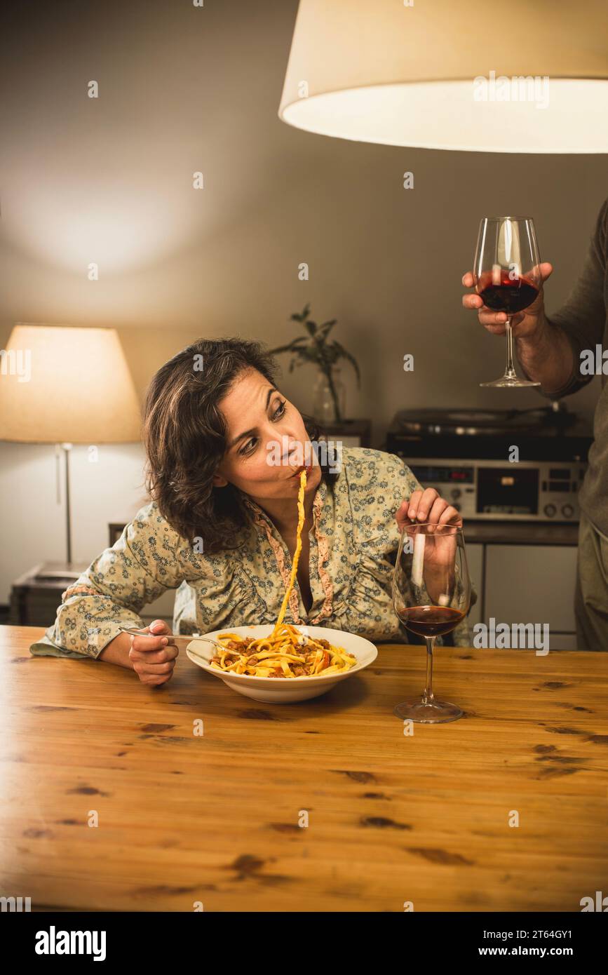 Frau isst einen Teller Tagliatelle al Ragu Bolognese in einem gemütlichen Speisesaal. Stockfoto