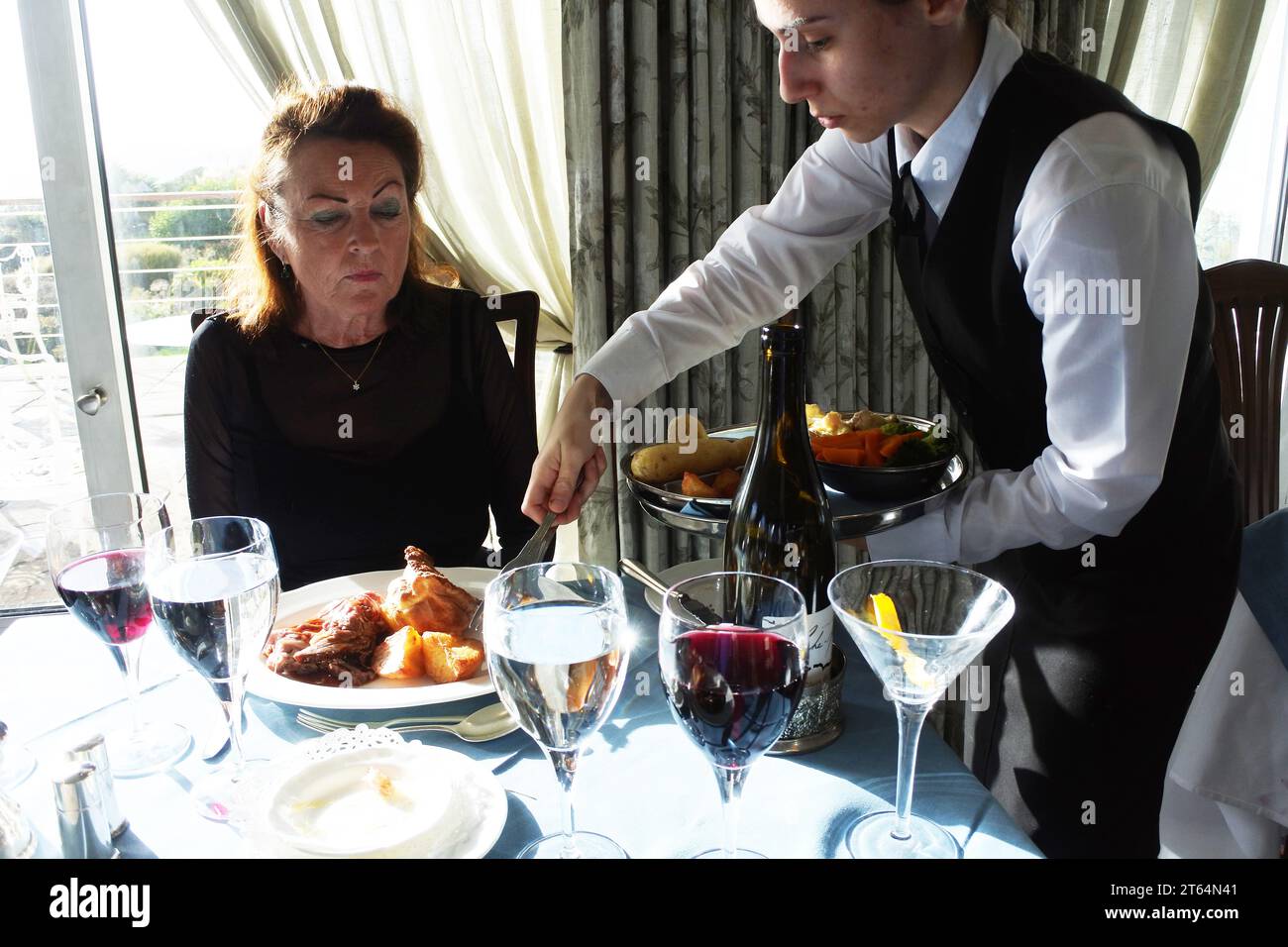 Reife Frau wird in einem Luxushotel - John Gollop - Abendessen serviert Stockfoto