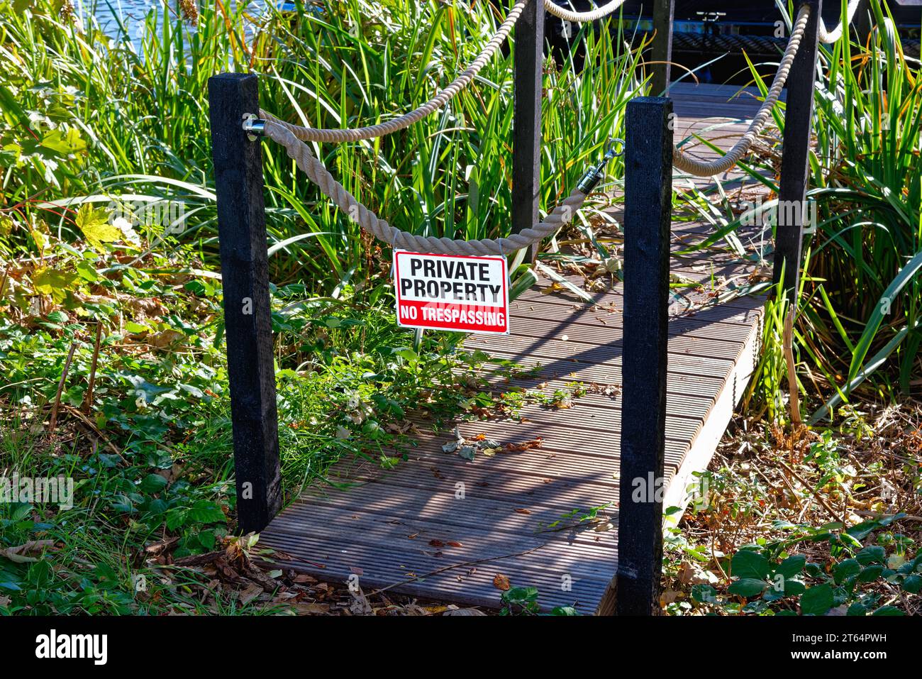 Ein Schild mit der Aufschrift Private Property No Trespassing an einem Seil an einem kleinen Steg an der Themse, Surrey England, Großbritannien Stockfoto