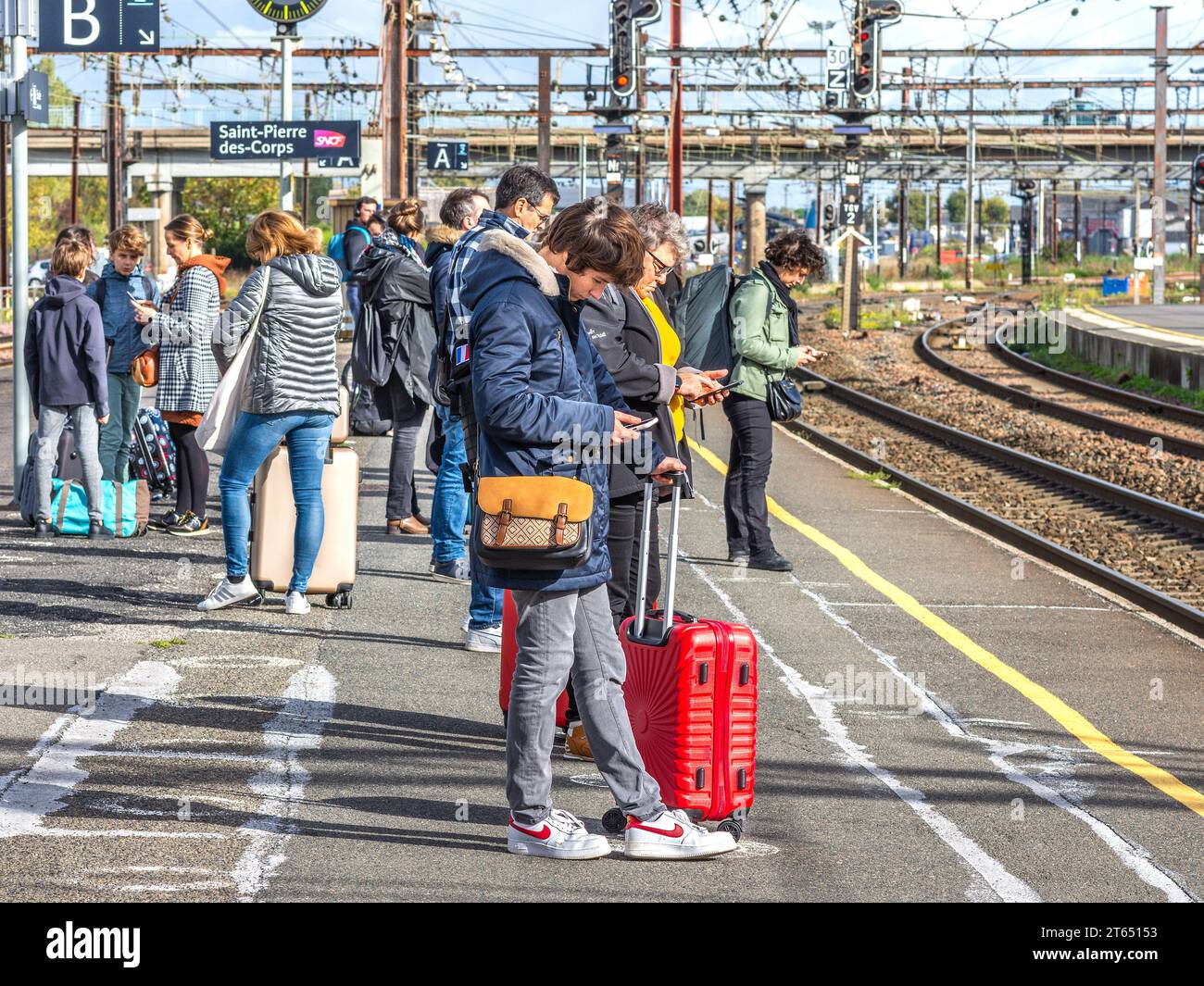 Passagiere, die Smartphones überprüfen und auf die Ankunft des TGV-Zuges am Bahnhof Saint-Pierre-des-Corps warten - Tours, Indre-et-Loire (37), Frankreich. Stockfoto
