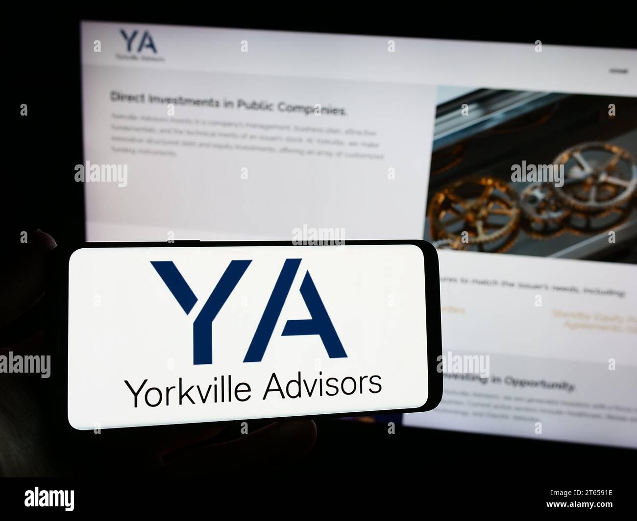 Person mit Smartphone und Logo der US-Investmentgesellschaft Yorkville Advisors Global LP vor der Website. Schwerpunkt auf dem Display des Telefons. Stockfoto