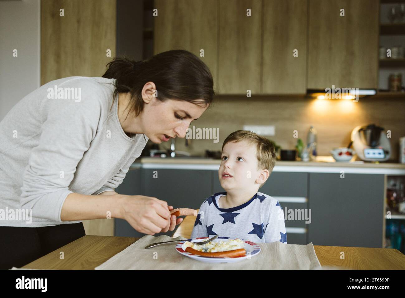 Mutter füttert ihrem Sohn liebevoll Bio-Frühstück in der Küche Stockfoto