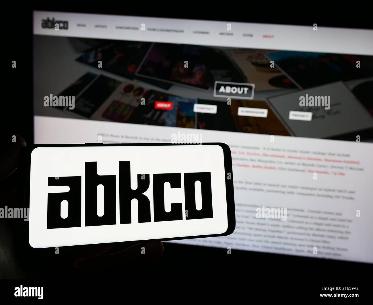 Person mit Smartphone und Logo des US-amerikanischen Plattenlabels ABKCO Music Records Inc. Vor der Website. Schwerpunkt auf dem Display des Telefons. Stockfoto