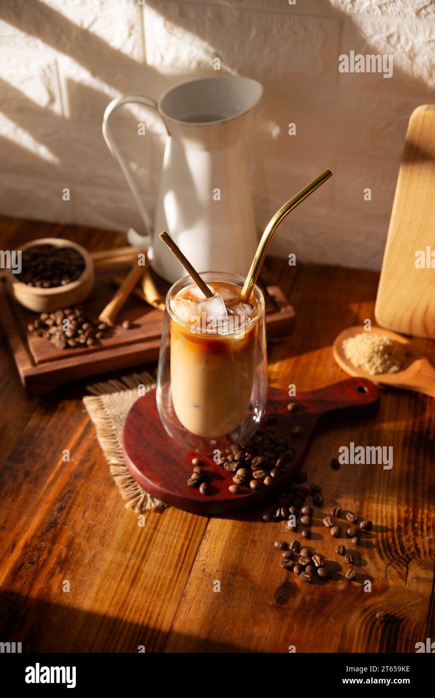 Eiskaffee serviert in einer doppelwandigen Glasschale und Metallstroh, ein kaltes Sommergetränk mit Eiswürfeln und Gewürzen, Zimt, Muskatnuss, Vanille, Mu Stockfoto