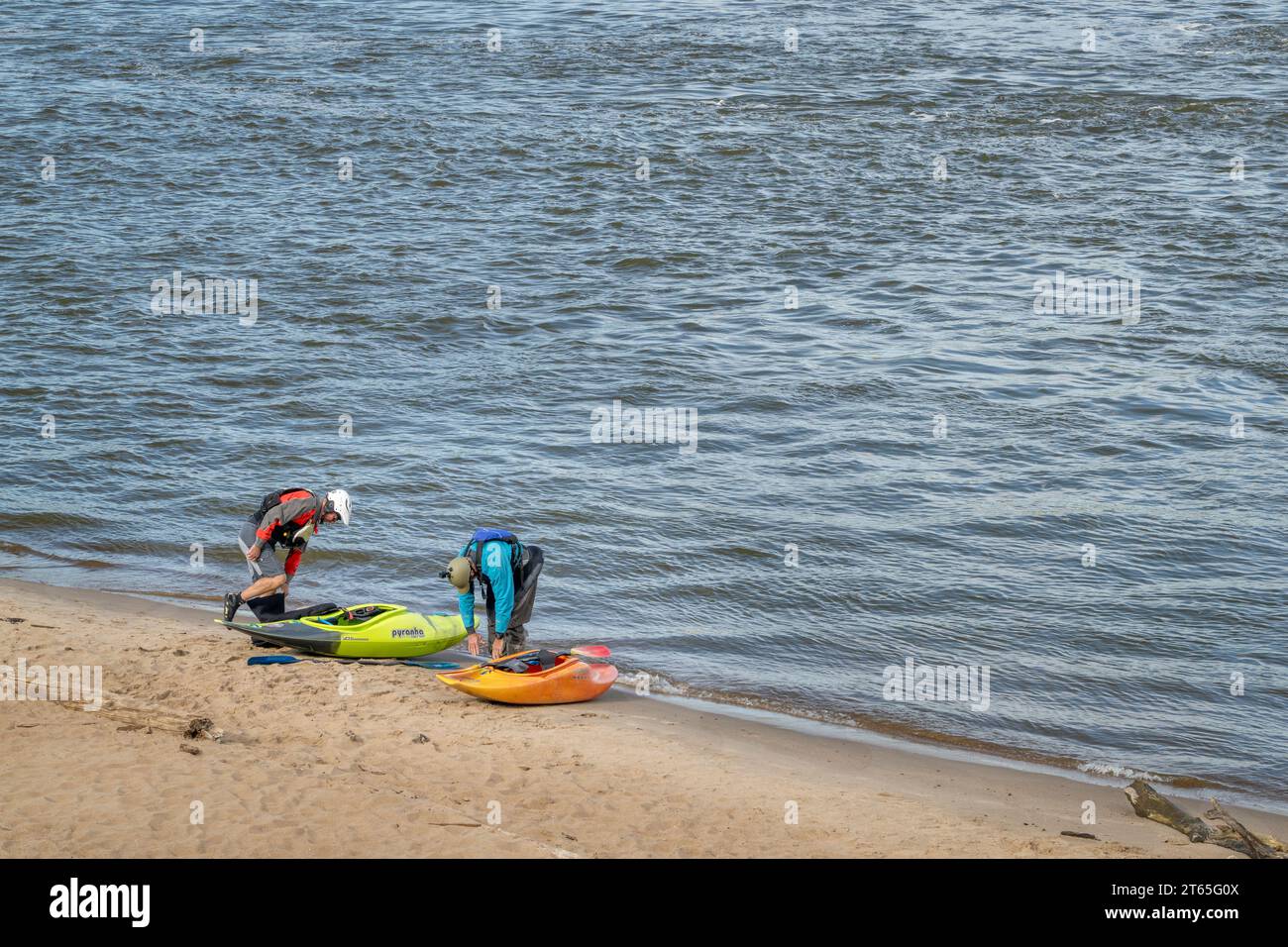 Granite City, Il, USA – 8. Oktober 2023: Zwei Kajakfahrer starten Wildwasserkajaks von einem Strand am Mississippi River unterhalb eines Wassers des Low W Stockfoto