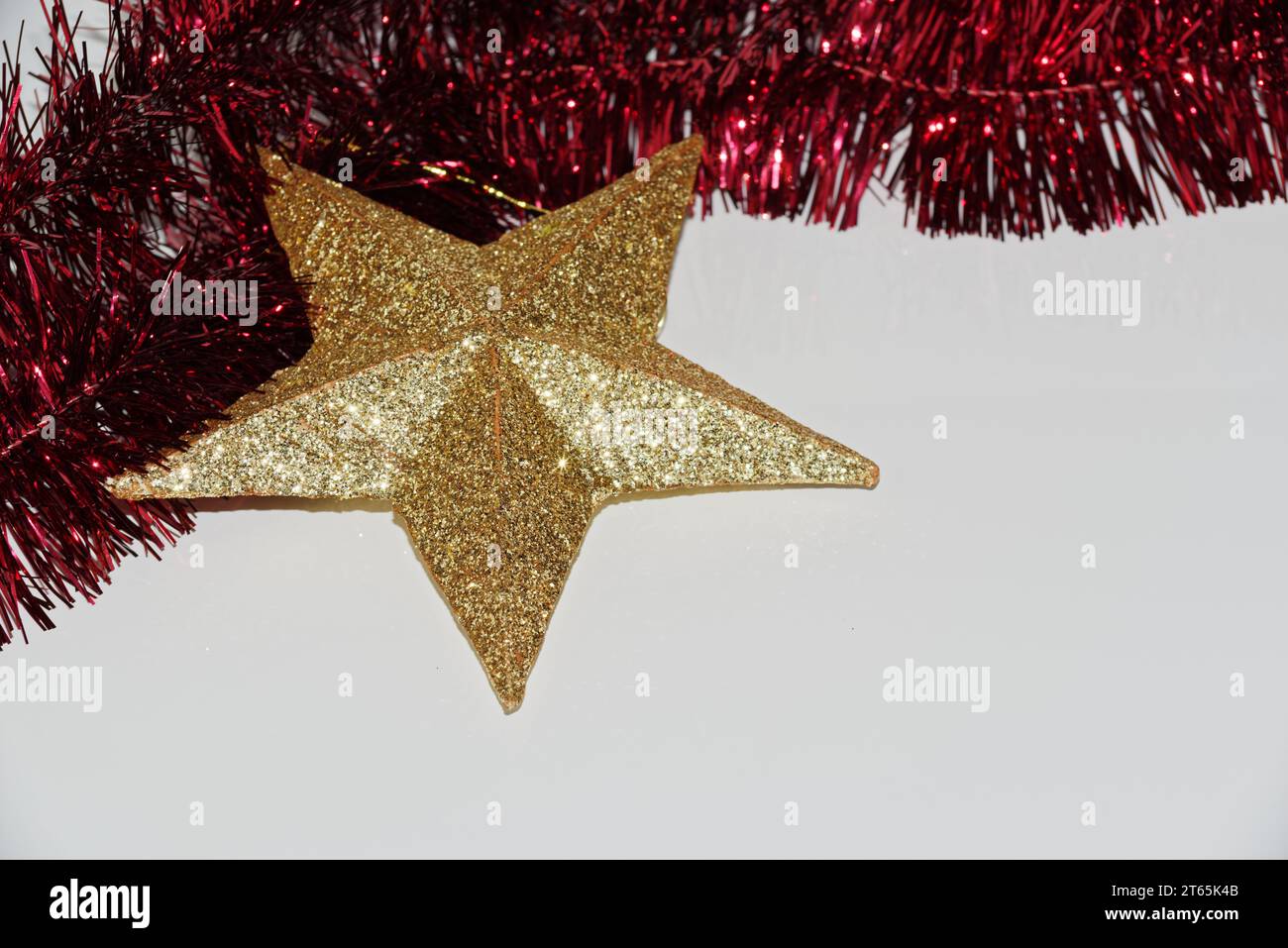 Goldener Weihnachtsstern und rotes Lametta auf weißem Hintergrund Stockfoto