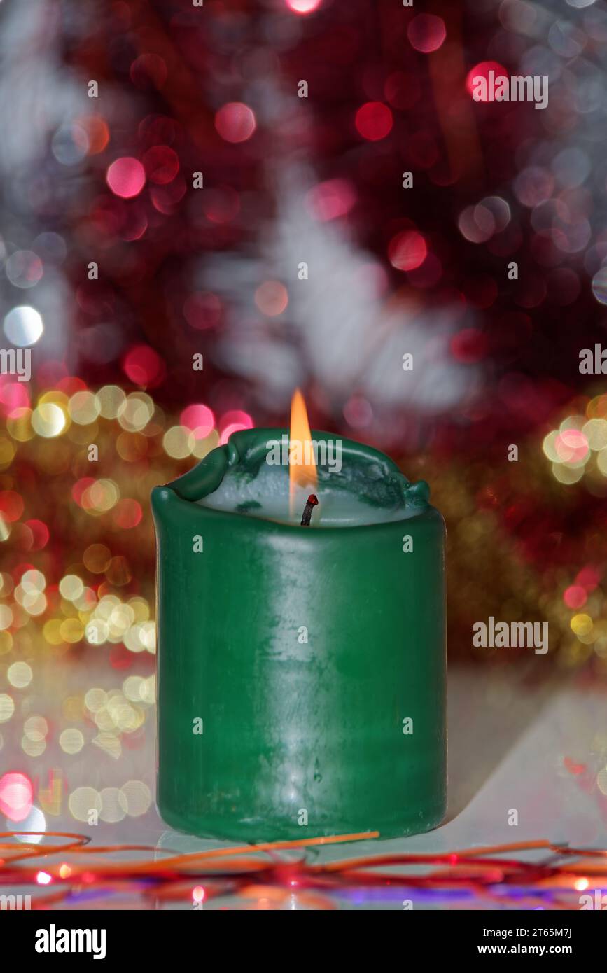 Einzelne grüne brennende Kerze vor verschwommenem Hintergrund. Konzentrieren Sie sich auf die Flamme Stockfoto
