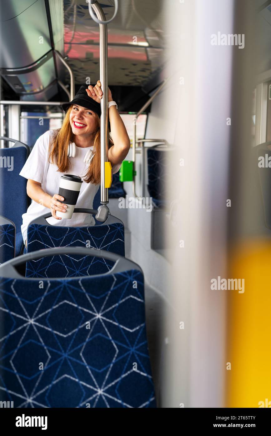 Eine junge Stadträtin mit Reisebecher sitzt im Shuttlebus. Passagier und Bus. Stockfoto