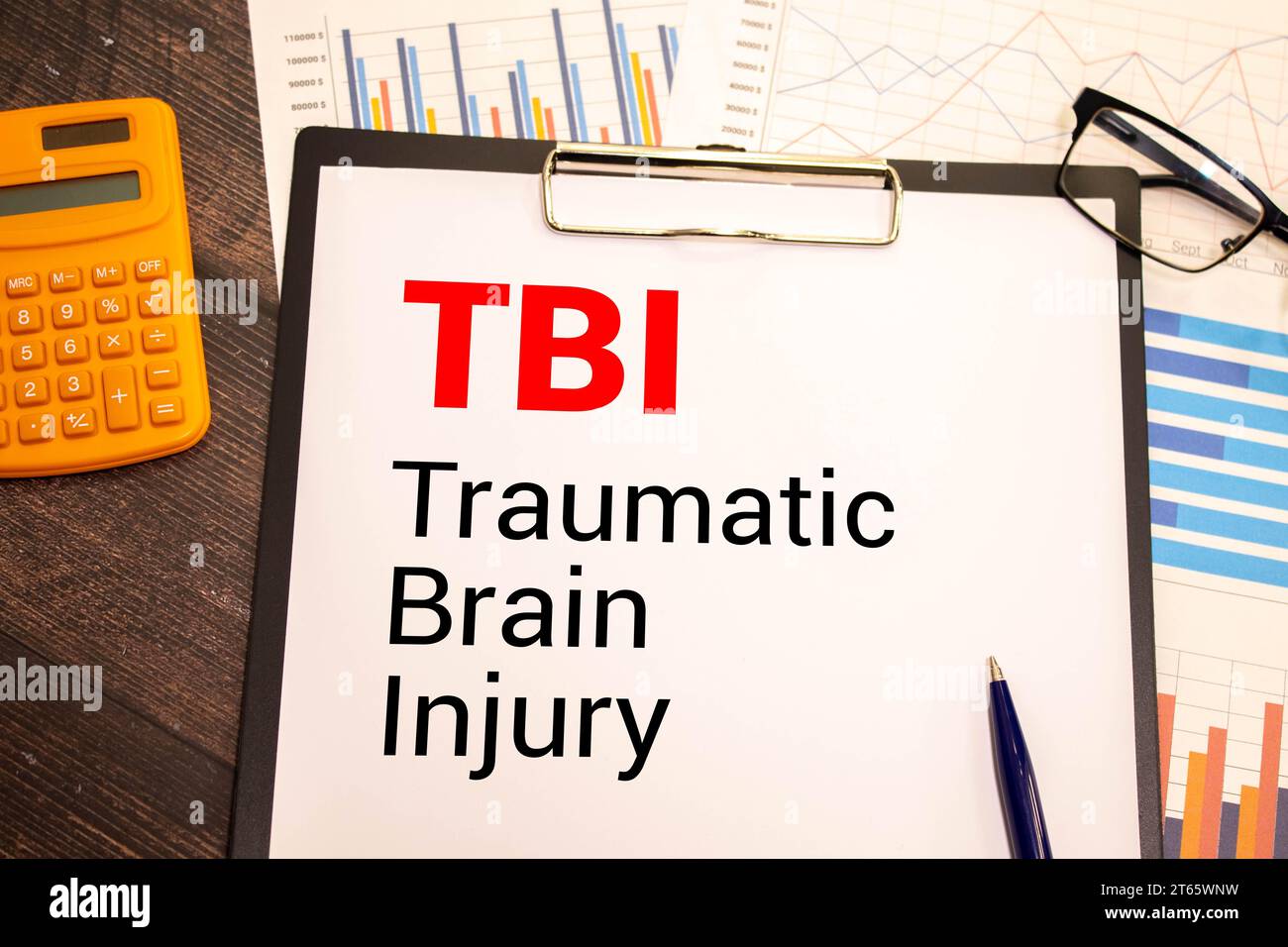 TBI-Symbol für Schädel-Hirn-Trauma. Konzeptbegriffe TBI-Schädel-Hirn-Trauma auf weißer Note auf einem wunderschönen Hintergrund von Dollarscheinen. Stift. Medizinisches an Stockfoto
