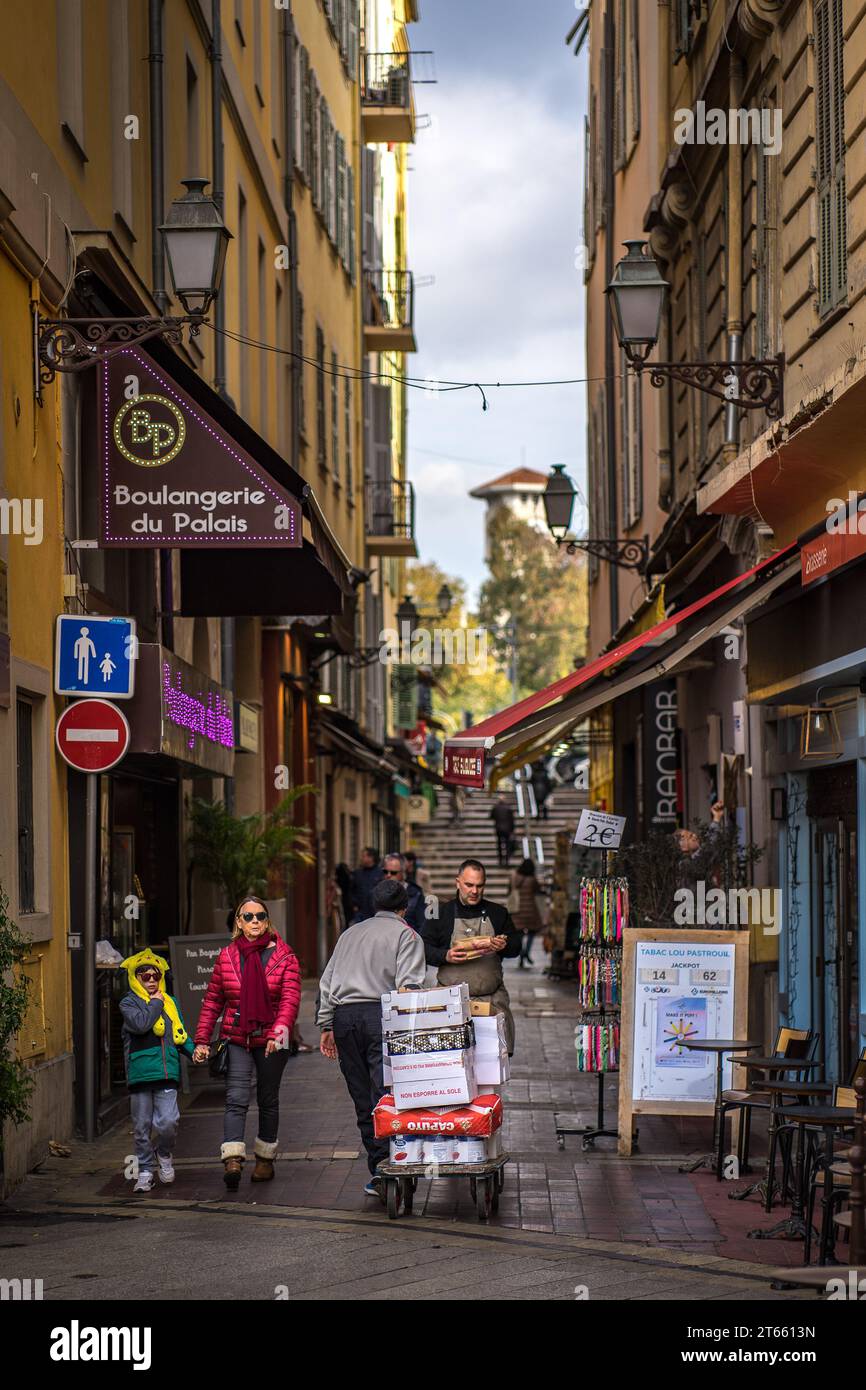 Nizza, Frankreich - 16. Februar 2023: Alltag auf der Straße in der Altstadt von Nizza, Frankreich, mit dem Turm der Masséna Gymnasium im Hintergrund Stockfoto