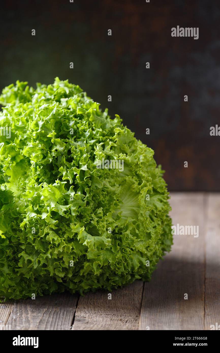 Ein großer Haufen frischer grüner Salatblätter auf einem Holztisch und mit dunklem Hintergrund. Gesunde Lebensmittel, Quelle von Mineralien und Vitaminen. Stockfoto