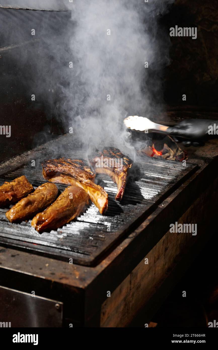 Appetitliche saftige Tomahawk-Steaks, Ribeye und Lendensteaks auf einem Grill über brennender Flamme beim Grillen. Gegrilltes Fleisch in einem Restaurant. Stockfoto