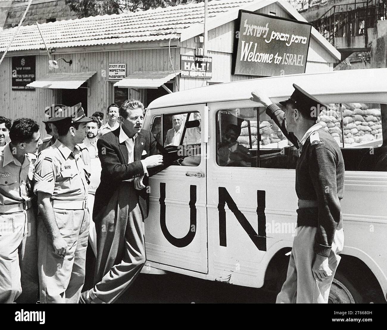 Danny Kaye lehnt sich gegen ein UN-Fahrzeug in der Nähe des Schildes mit der Aufschrift 'Willkommen in Israel', Israel, 1956 Stockfoto