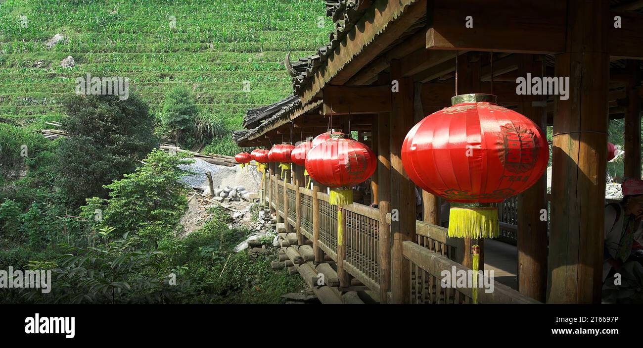 龙胜镇 (龙胜县) 中國 Longsheng, Longji Ping'an Zhuang, China; Rote Chinesische Laternen hängen auf einer hölzernen überdachten Brücke; Rote chinesische Laternen Stockfoto