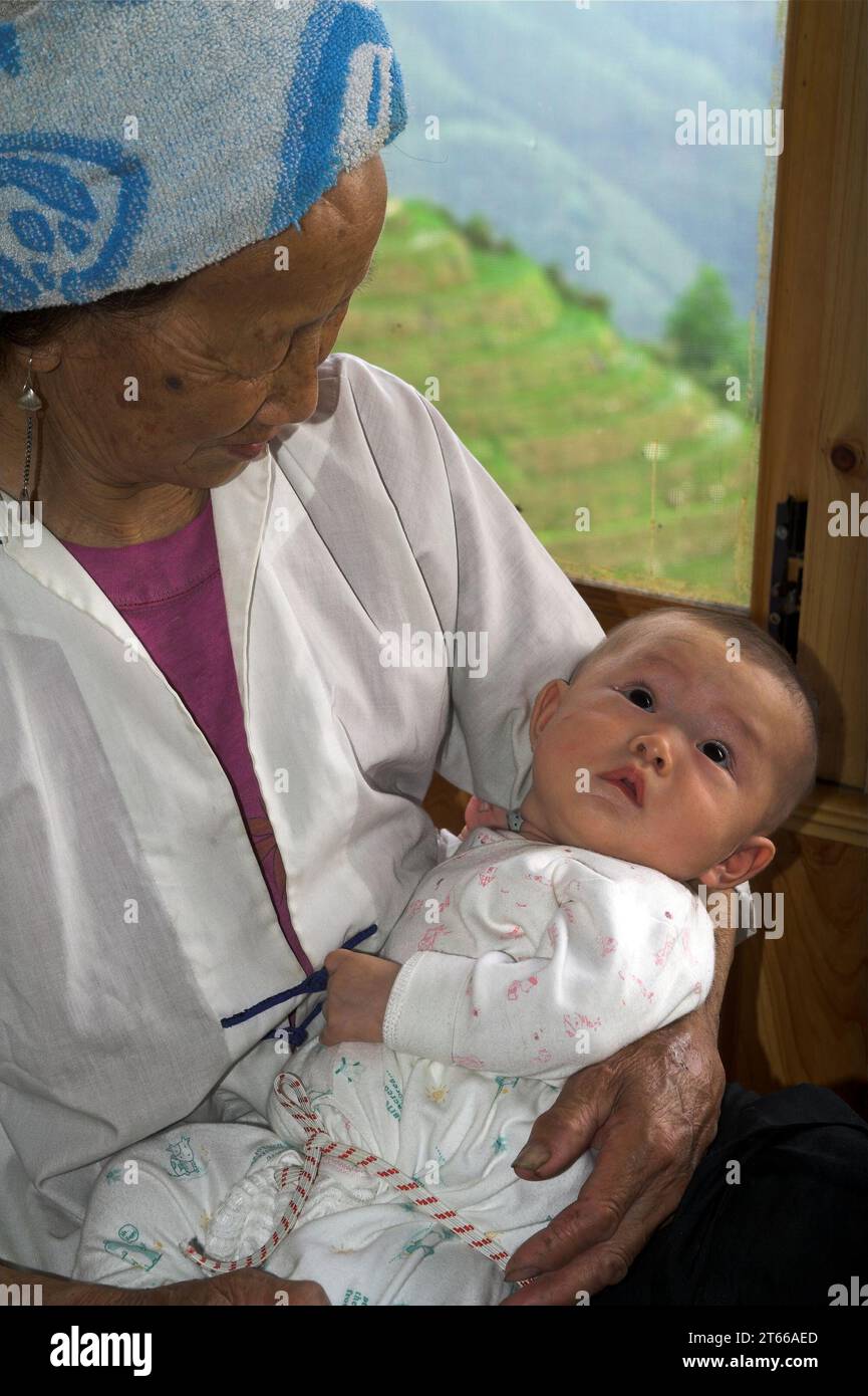龙胜镇 (龙胜县) 中國 Longsheng, Longji Ping'an Zhuang, China; Großmutter hält ein Baby in den Armen; Großmutter hält ein Baby im Arm Stockfoto