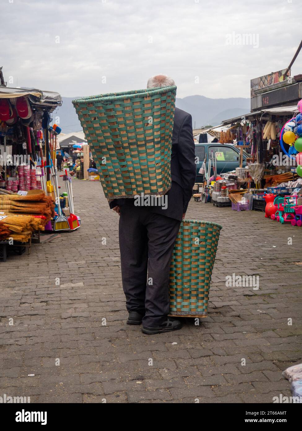 Batumi, Georgien. 10.29.2023 ein alter Mann mit einem Korb hinter dem Rücken auf dem Markt. Verkäufer von Waren. porter Stockfoto