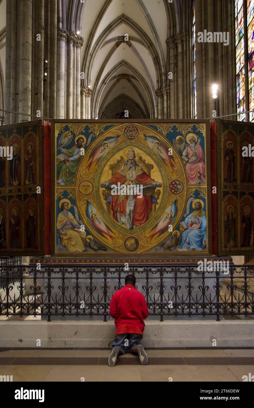 Der Mensch kniet im Gebet vor der Altarmalerei im Kölner Dom. Stockfoto