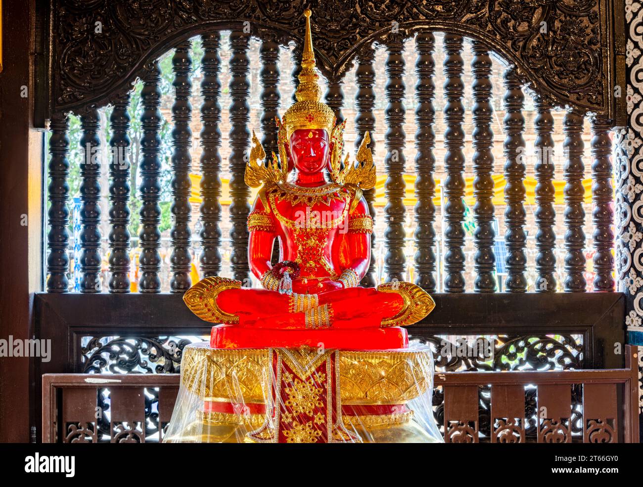 Sonnenlicht, das durch das transparente Buddha-Bild leuchtet, im Inneren des Tempels, wunderschön, lebendig, verziert rot und goldfarben, vor einem Fenster in der Nähe Stockfoto