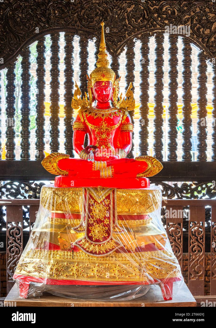 Sonnenlicht, das durch das transparente Buddha-Bild leuchtet, im Inneren des Tempels, wunderschön, lebendig, verziert rot und goldfarben, vor einem Fenster in der Nähe Stockfoto