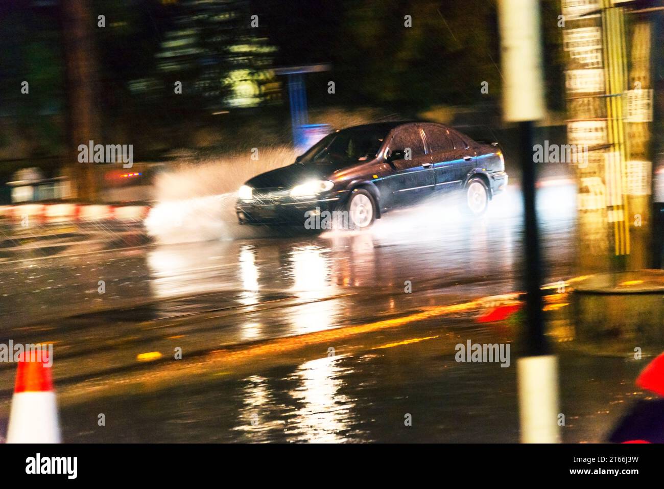 Chiang Mai, Thailand-16. März 2023: Autos rasen gefährlich entlang des Umkreises der Altstadt von Chiangmai durch Regenpfützen in einem sintflutartigen Regenguss Stockfoto