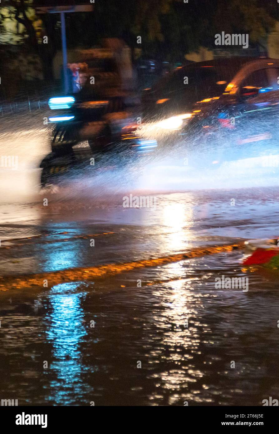 Chiang Mai, Thailand-16. März 2023: Autos rasen gefährlich entlang des Umkreises der Altstadt von Chiangmai durch Regenpfützen in einem sintflutartigen Regenguss Stockfoto
