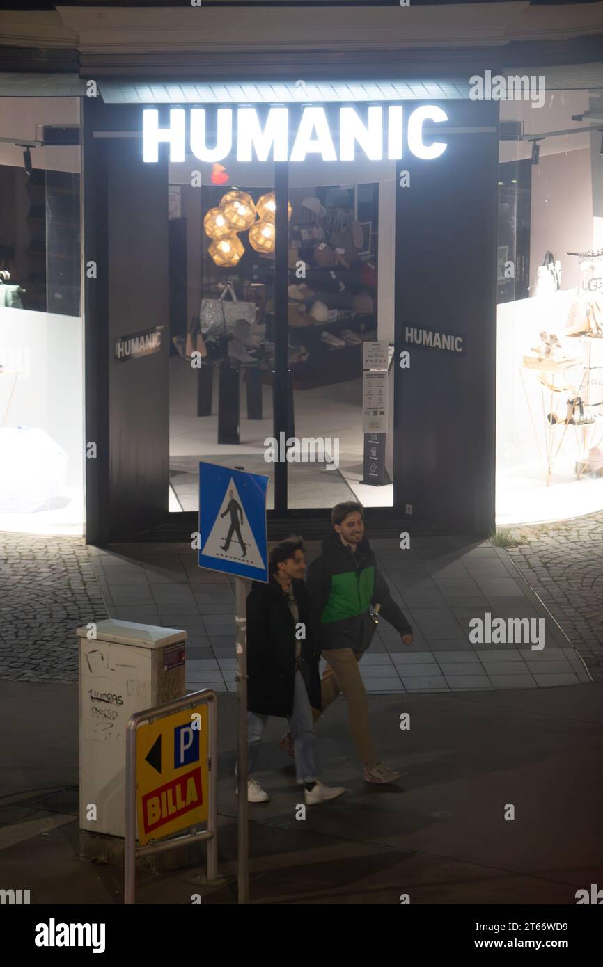 Zwei Mann spazieren nachts im Winter vor dem Humanic Store in Wien Österreich, fotografiert von einem hohen Gebäude Stockfoto