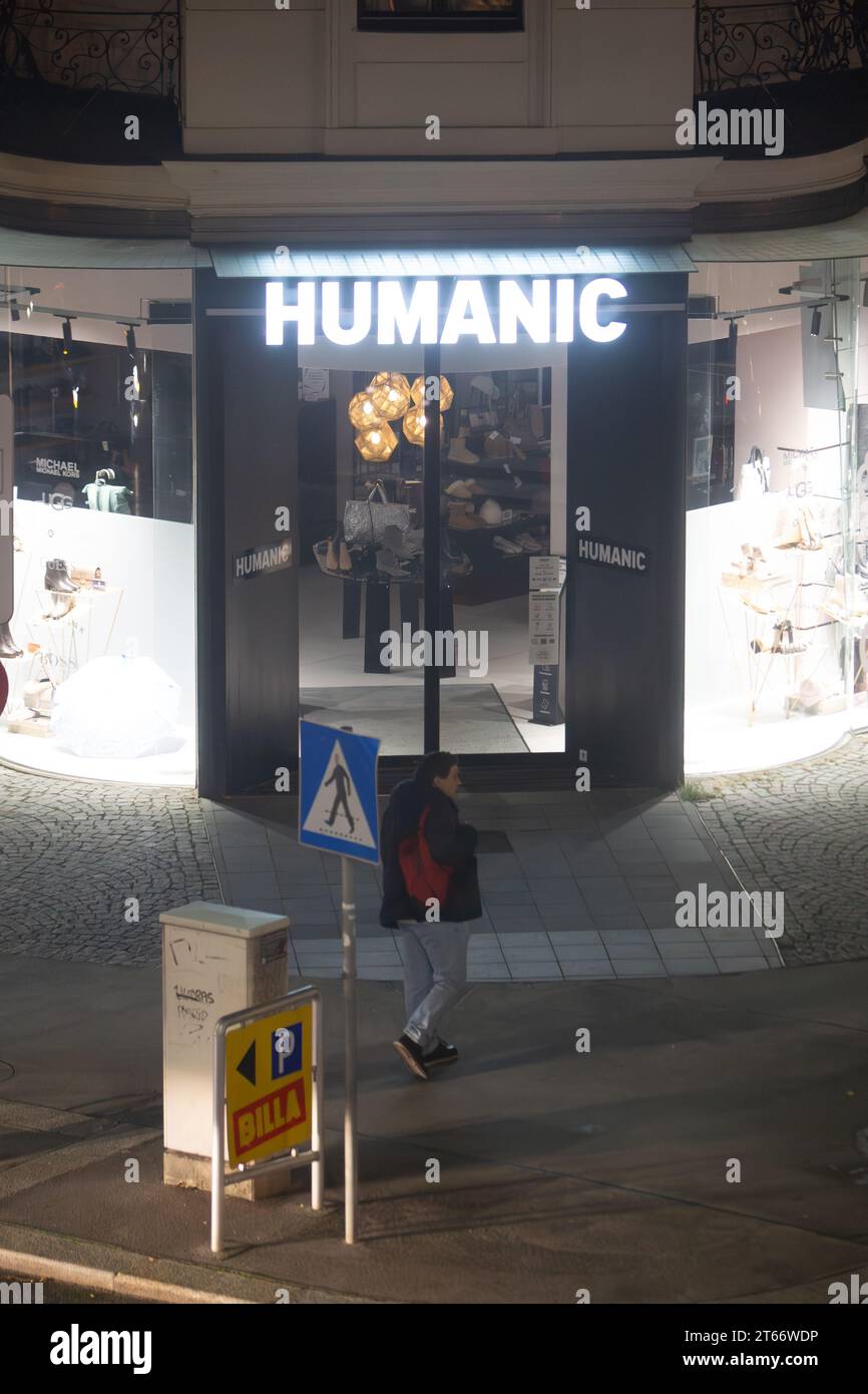 Ein Mann läuft nachts im Winter vor dem Humanic Store in Wien Österreich, fotografiert von einem hohen Gebäude Stockfoto