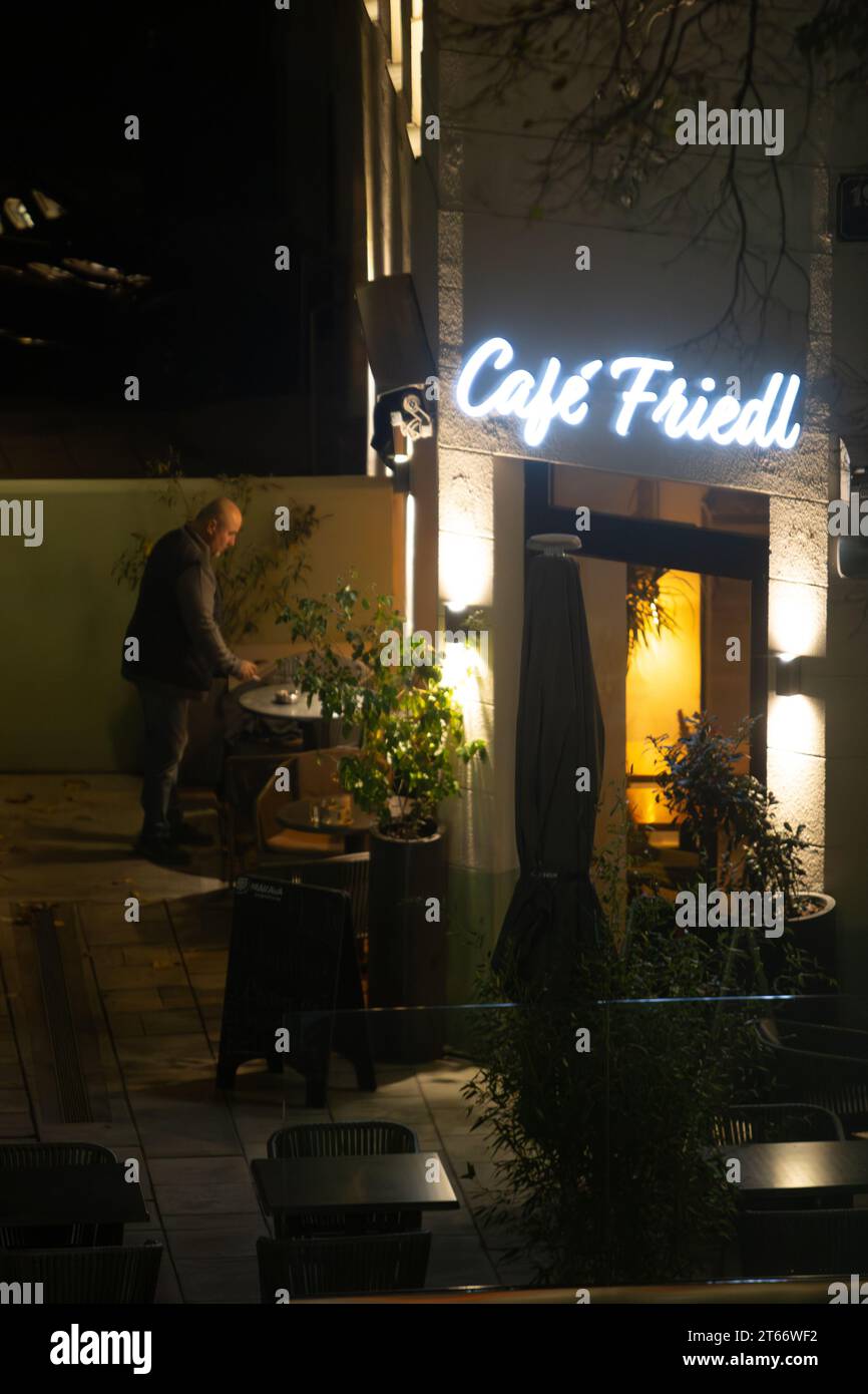 Ein kahler Mann raucht, während er an einem Winterabend beiläufig vor einem Café steht, Wien Österreich, Stockfoto