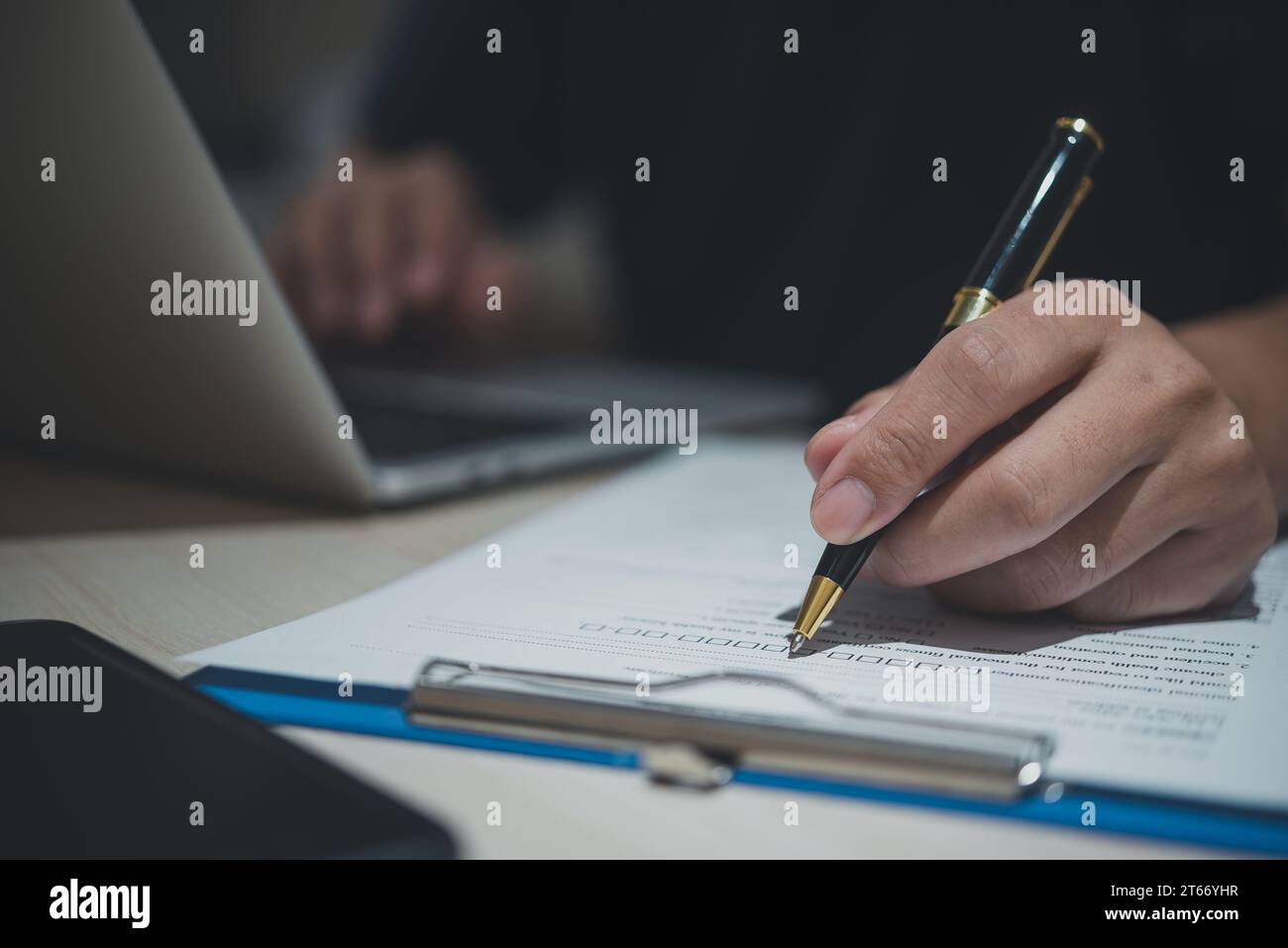 Ein männlicher Mitarbeiter erstellt derzeit eine Bewerbung an seinem Arbeitsplatz. Geschäftsdokument, Vertrag unterzeichnen. Stockfoto