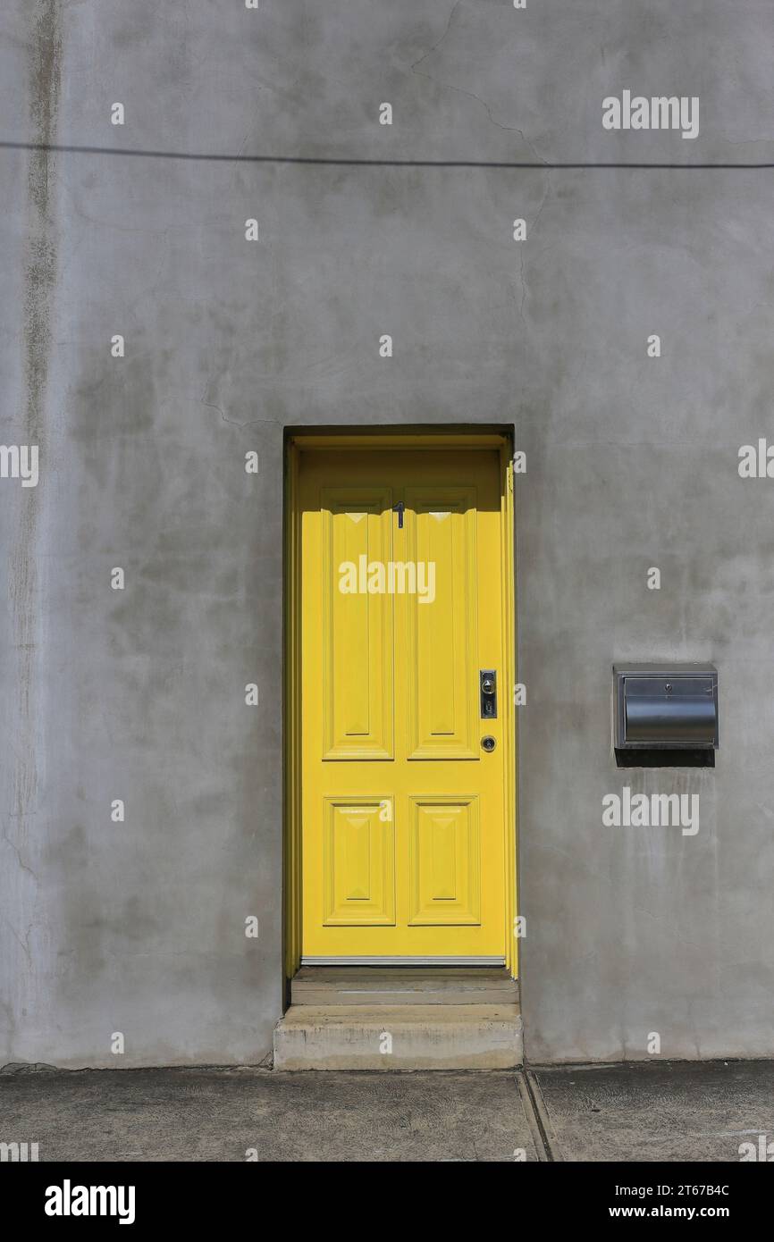 Gelbe Tür in einer einfachen Betonfassade mit moderner Architektur. Stockfoto
