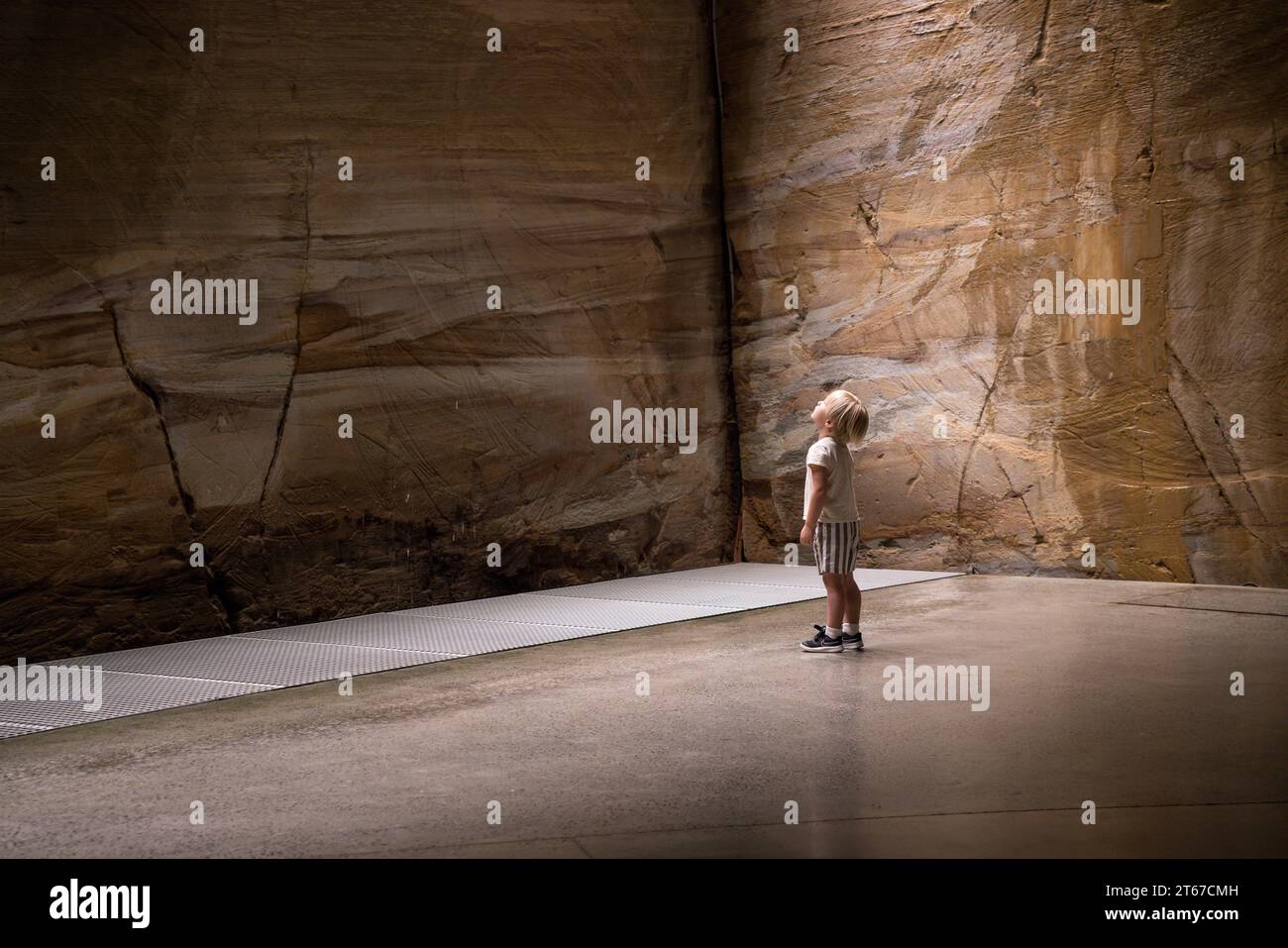 Ein kleines Kind blickt auf eine Sandsteinwand-Ausstellung in der Mona Gallery Tasmania. Stockfoto