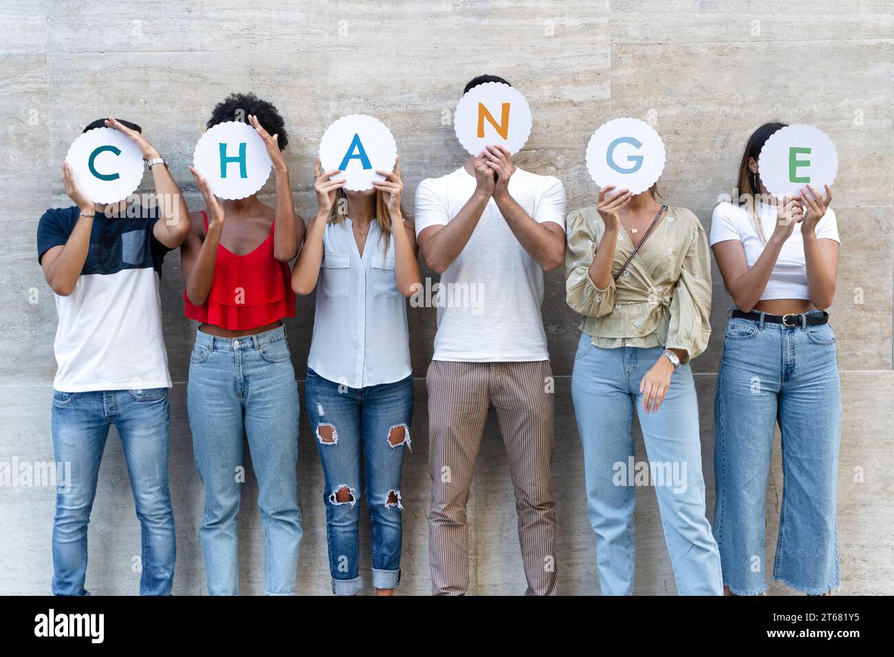 Eine Gruppe von verschiedenen Personen, die zusammen stehen und jeweils einen Brief in der Hand halten, um das Wort „VERÄNDERUNG“ zu beschreiben. Stockfoto