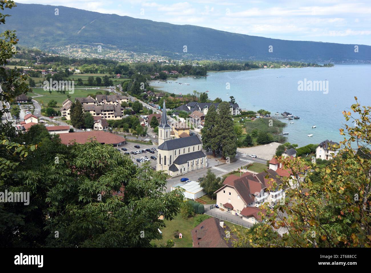 Blick aus der Vogelperspektive oder Hochwinkelblick über das Dorf Duingt am Seeufer mit Kirche und Dorfplatz und See Annecy oder Lac d'Annecy Haute Savoie Frankreich Stockfoto