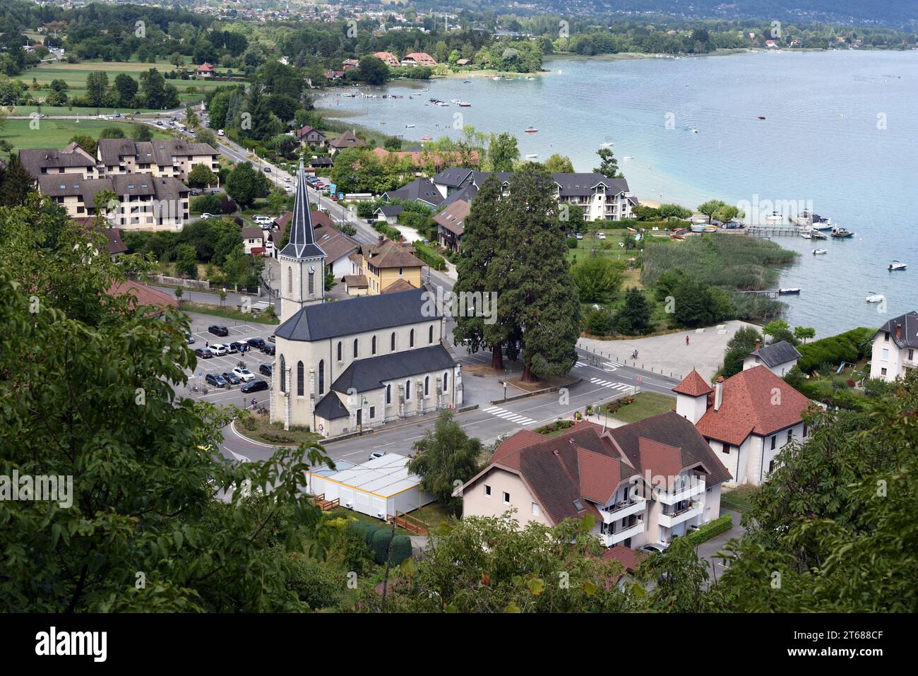 Blick aus der Vogelperspektive oder Hochwinkelblick über das Dorf Duingt am Seeufer mit Kirche und Dorfplatz und See Annecy oder Lac d'Annecy Haute Savoie Frankreich Stockfoto